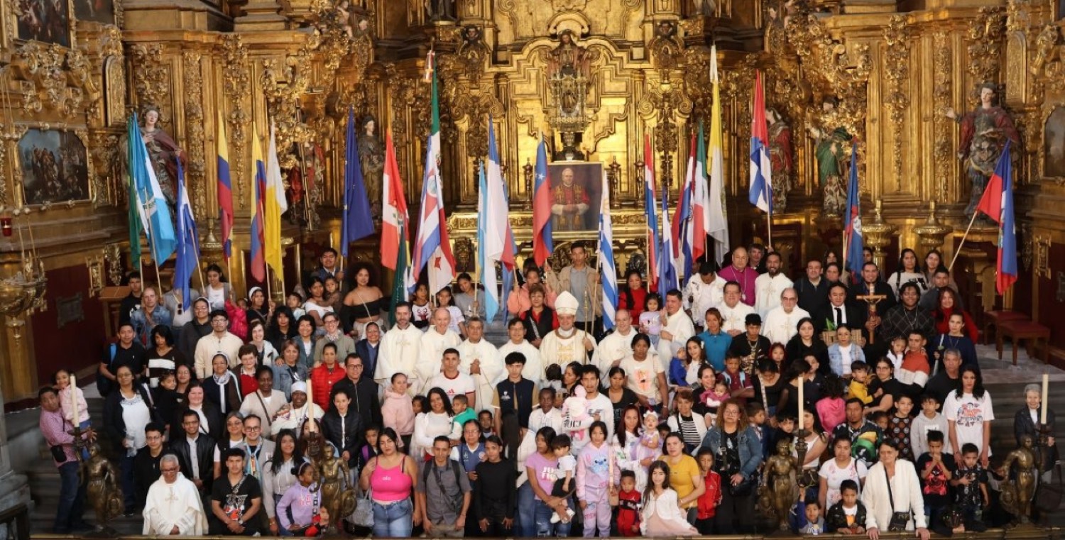 Fotografía de grupo en el jubileo: cientos de personas migrantes con banderas de sus países junto a obispos y sacerdotes en el altar de una iglesia