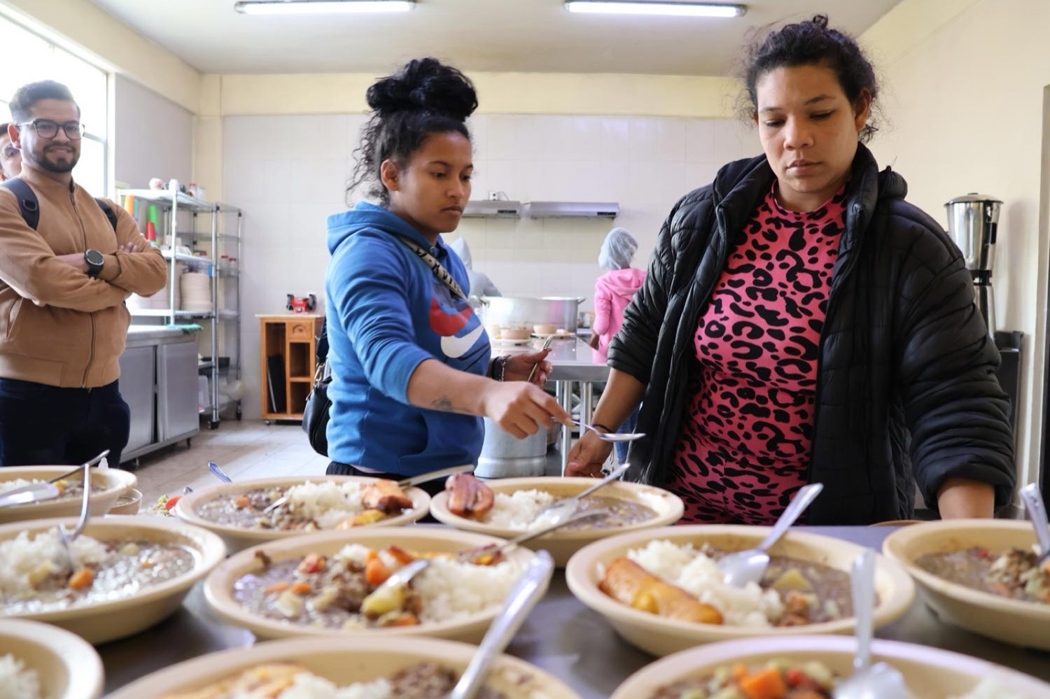 Personas atendidas reciben platos de comida caliente en el comedor de la fundación