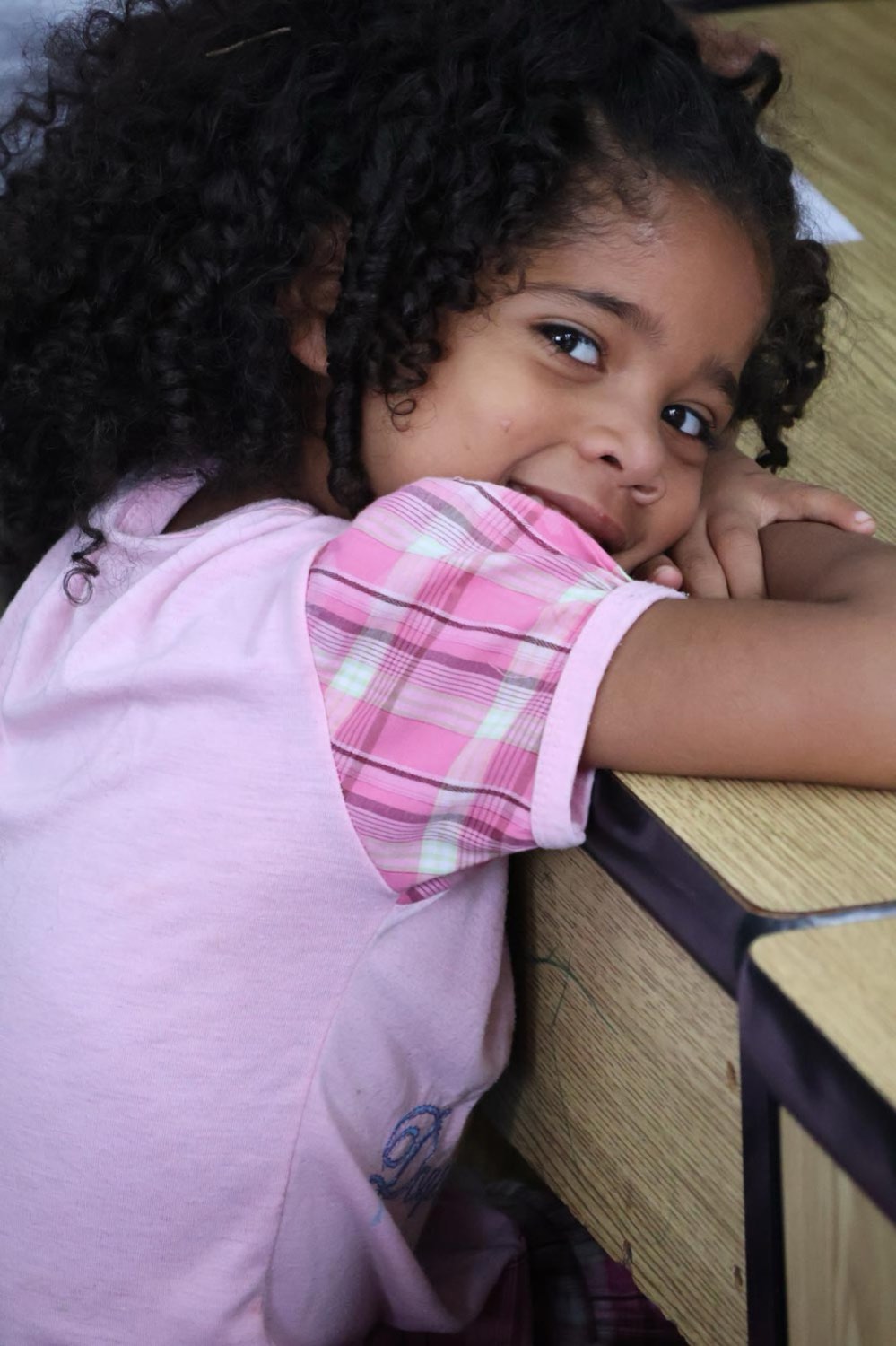 Niña recostada sobre una mesa en el aula de actividades